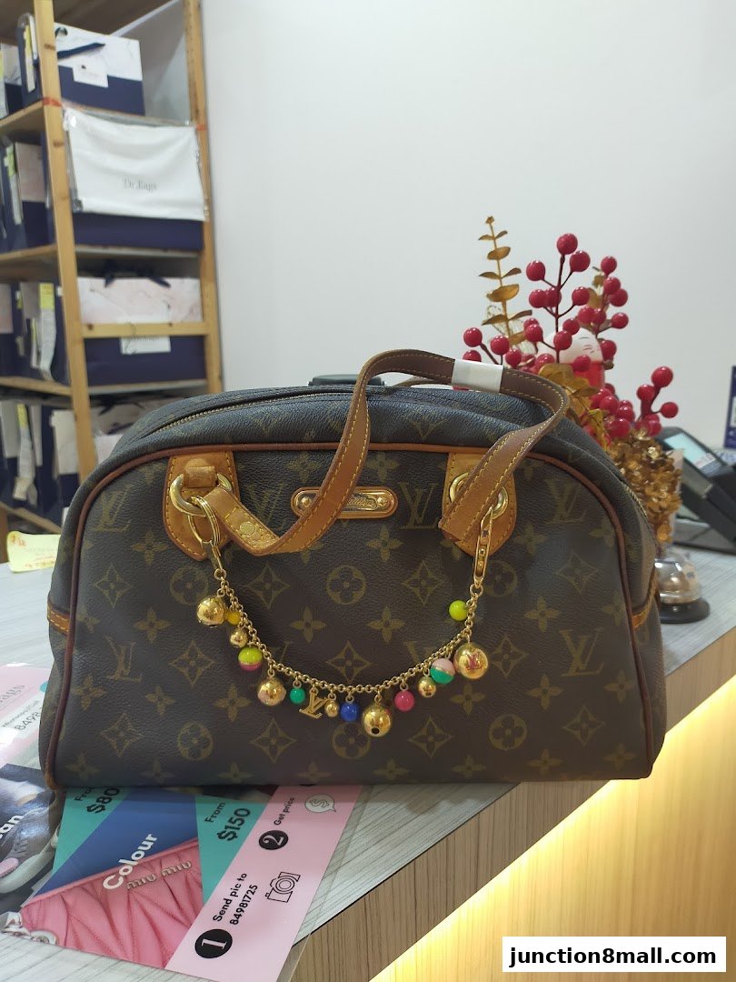 A designer handbag with colorful charms displayed on a counter with promotional flyers.