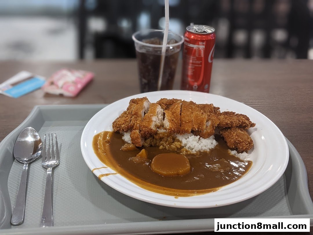 A plate of Japanese curry with katsu, rice, and a can of Coca-Cola.
