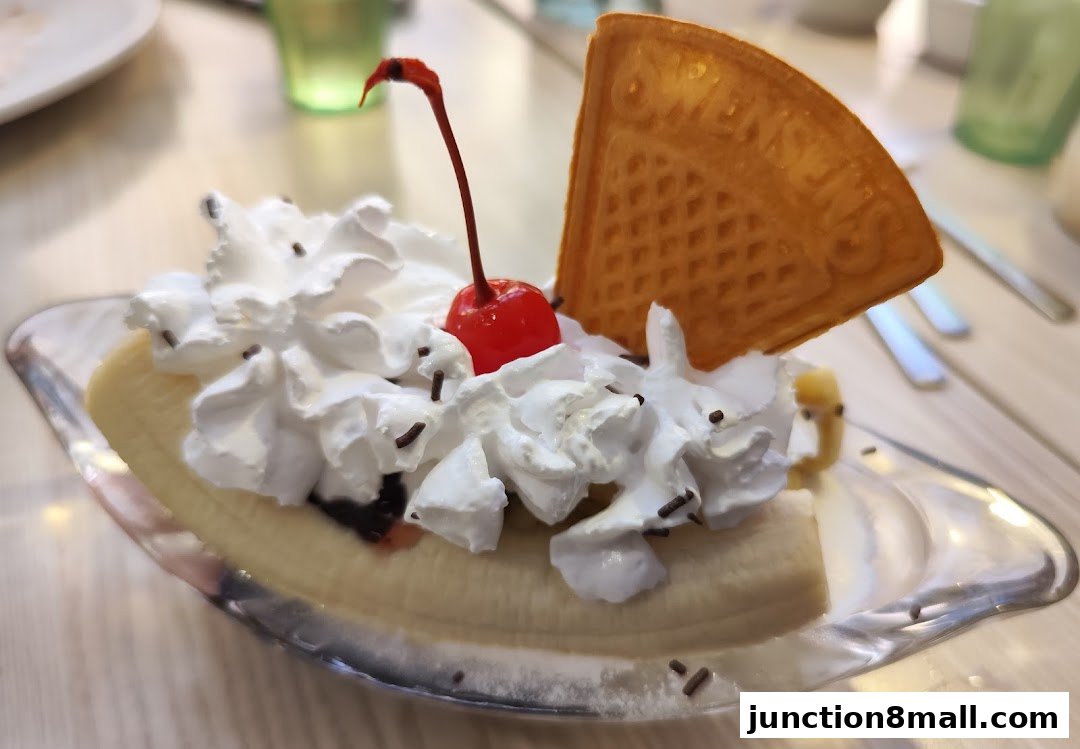 A delicious banana split dessert with whipped cream, a cherry, and a waffle.