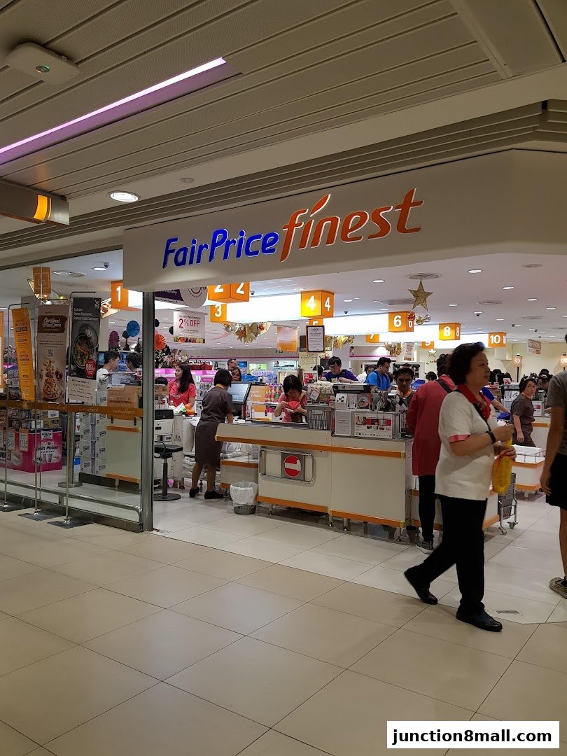 The entrance of a FairPrice Finest supermarket with checkout counters and staff serving customers.