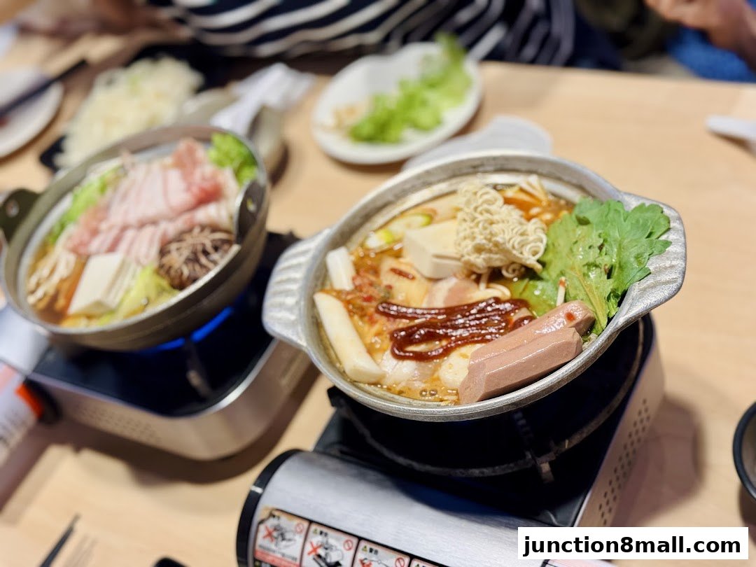 Two steaming hot pots filled with ingredients like meat, vegetables, and noodles.