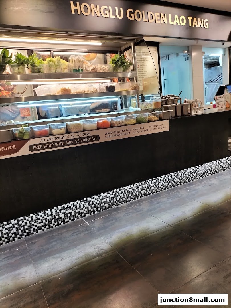 A food stall counter displaying fresh ingredients and soup base options.