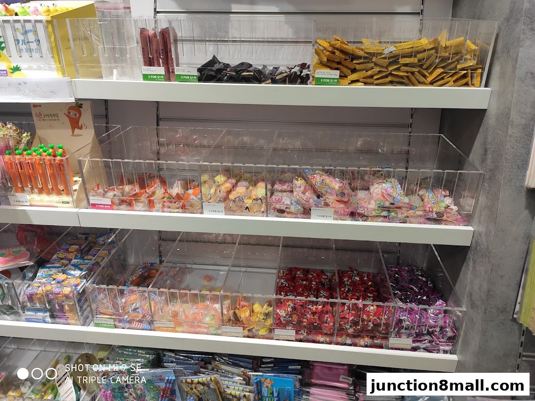 Shelves stocked with various candies, pens, and snacks in clear display bins.
