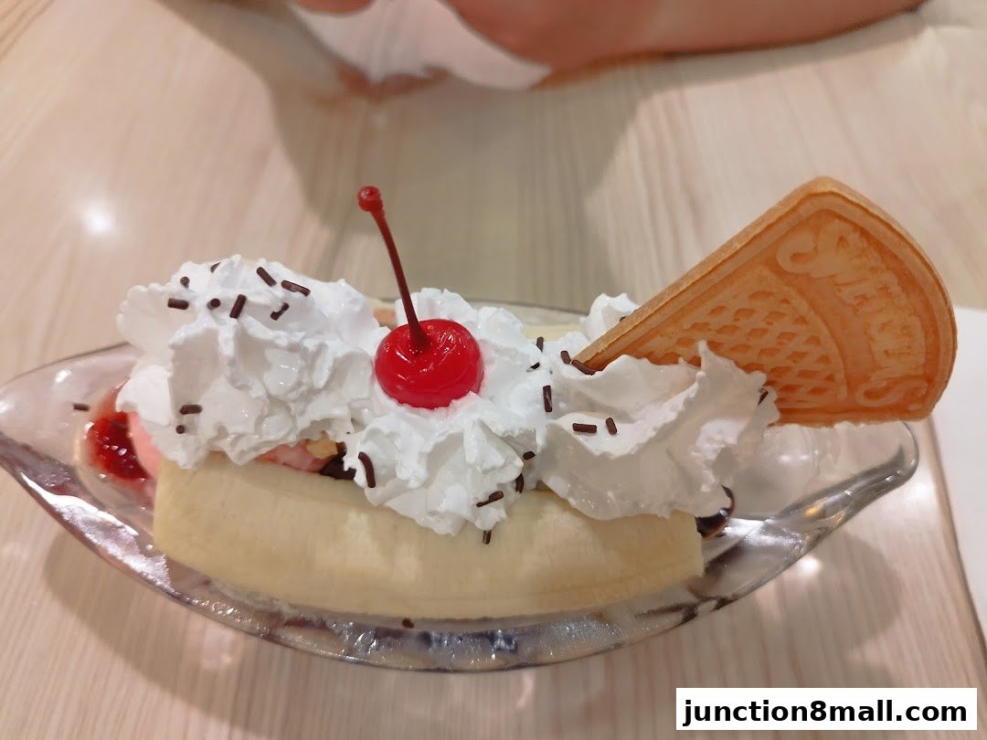 A delicious banana split dessert with whipped cream, cherry, sprinkles, and a waffle.
