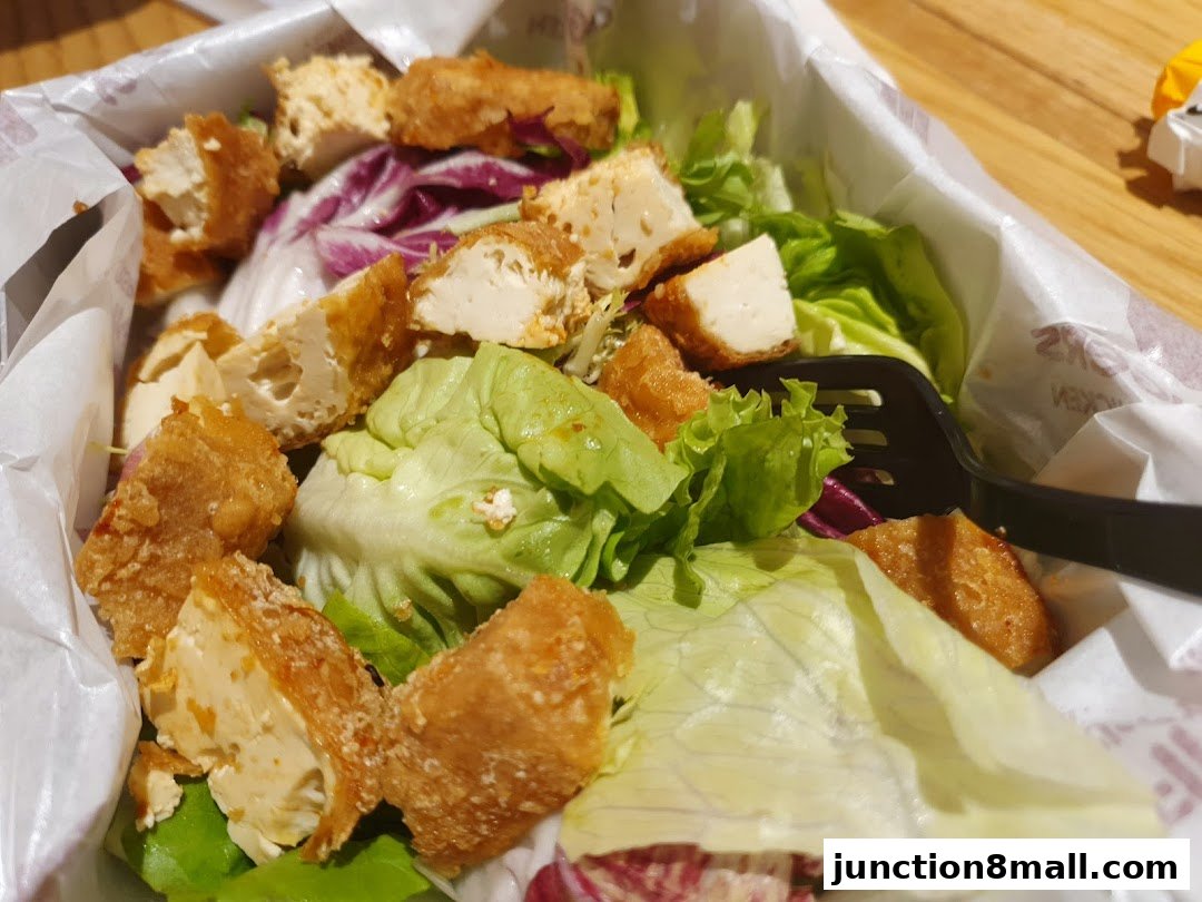 A close-up of a crispy chicken salad with lettuce and tofu pieces.