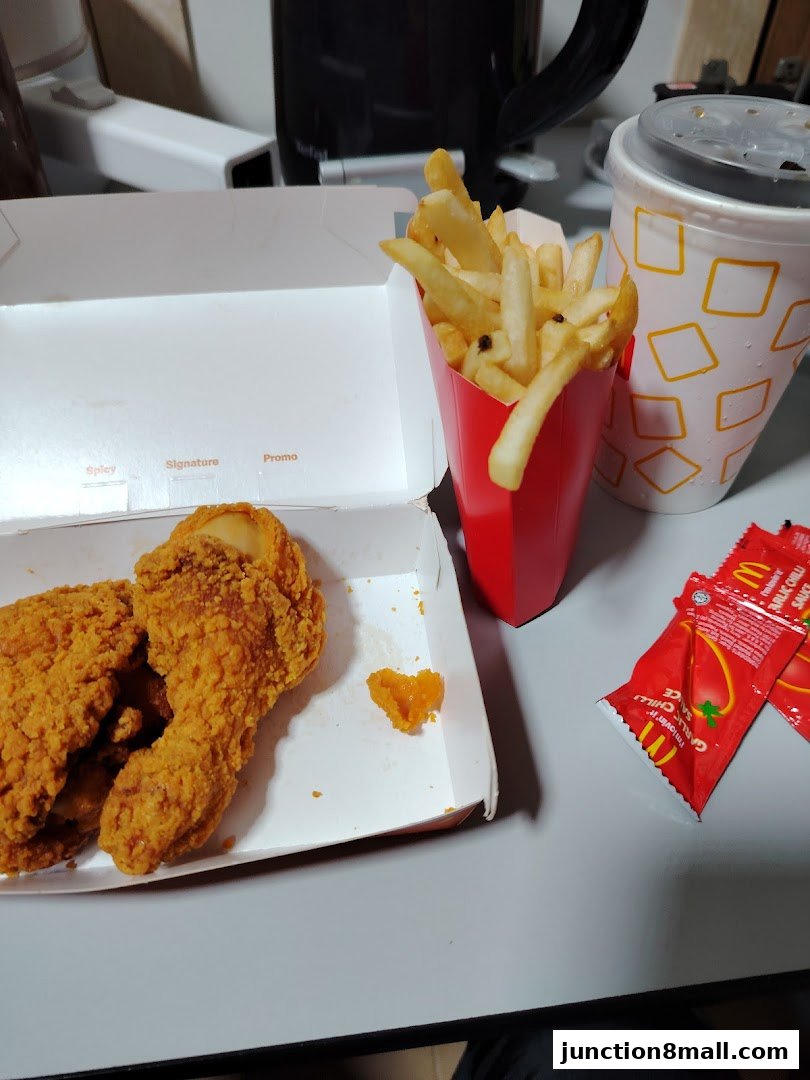 A box of McDonald's fried chicken with fries, a drink, and sauce packets.