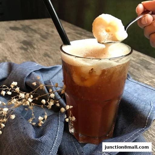 A refreshing iced drink with a scoop of foam on a spoon, garnished with delicate white flowers.