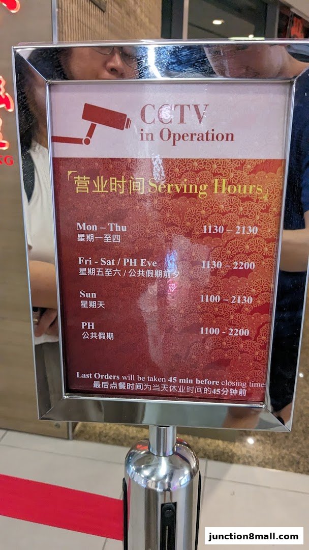 A sign displaying serving hours and CCTV in operation for Din Tai Fung.