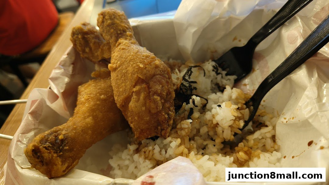 Crispy fried chicken drumsticks served with rice and seaweed in a takeaway container.