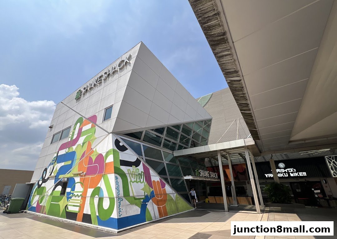 The exterior of a Shake Shack restaurant with a modern, angular design and colorful mural.