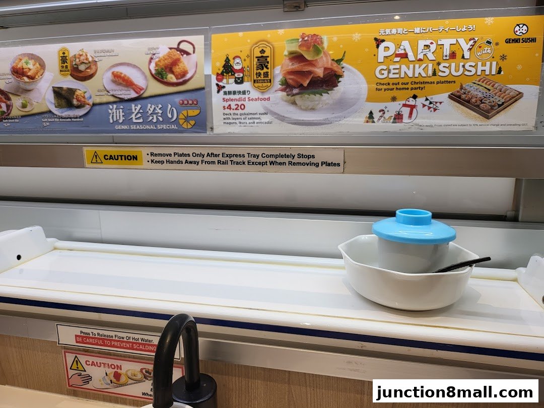A conveyor belt sushi restaurant with various sushi dishes and promotional signs.