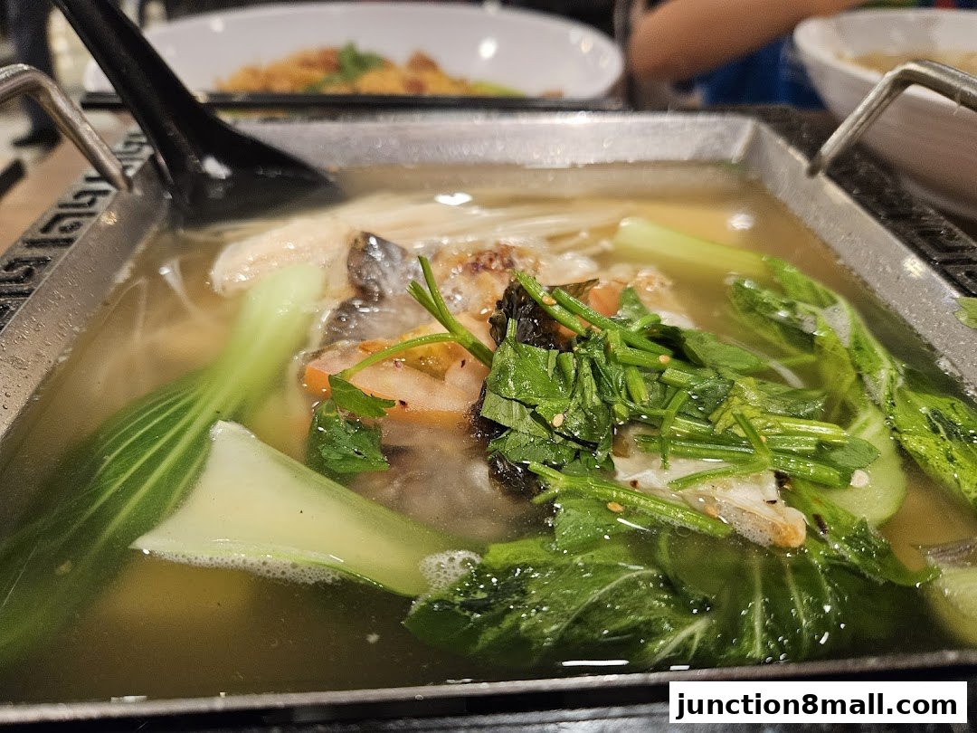 A close-up shot of a steaming hot pot dish with bok choy and other vegetables.
