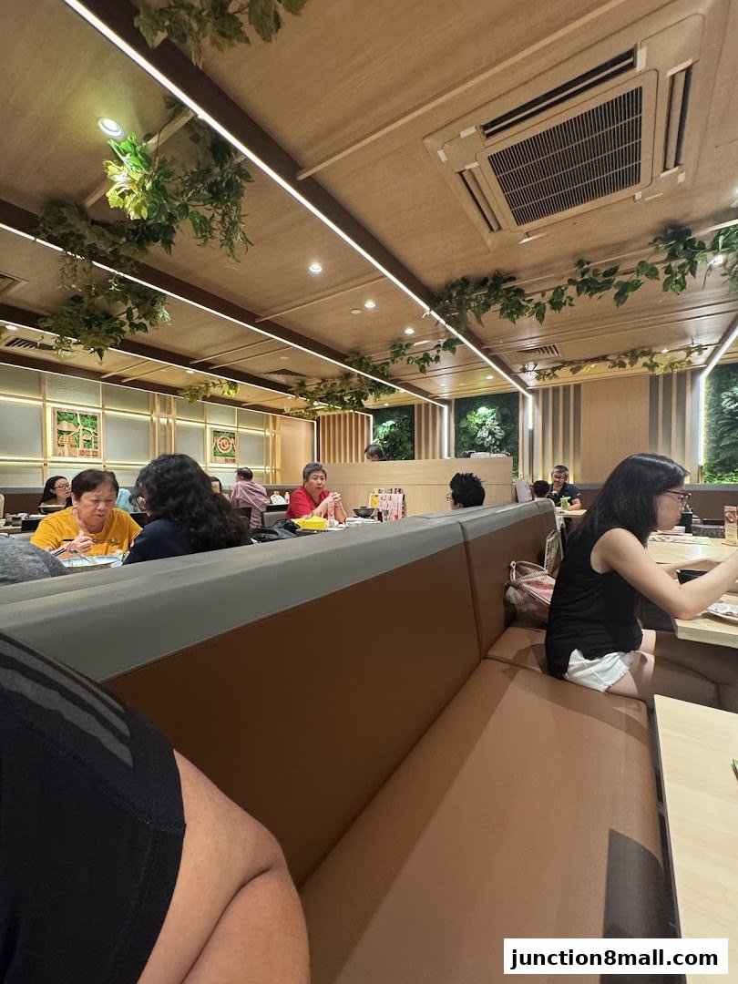 Interior view of a Japanese dining restaurant with patrons seated at tables and decorative plants.