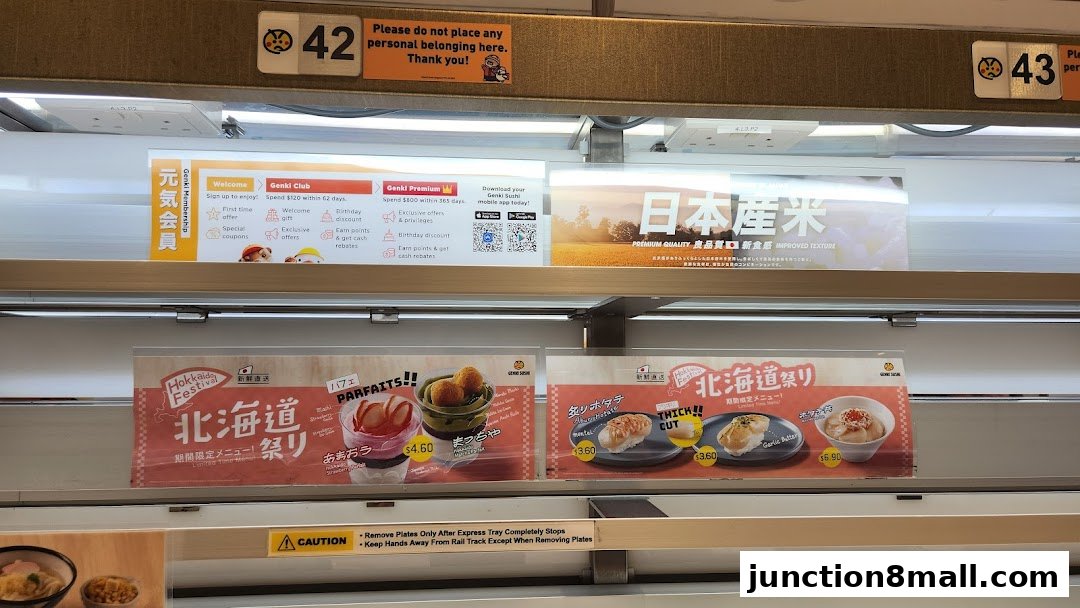 Conveyor belt sushi restaurant with promotional signs for Hokkaido Festival and premium rice.