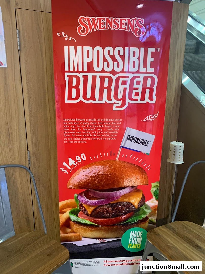 A promotional poster for Swensen's Impossible Burger, featuring a large image of the burger and its ingredients.