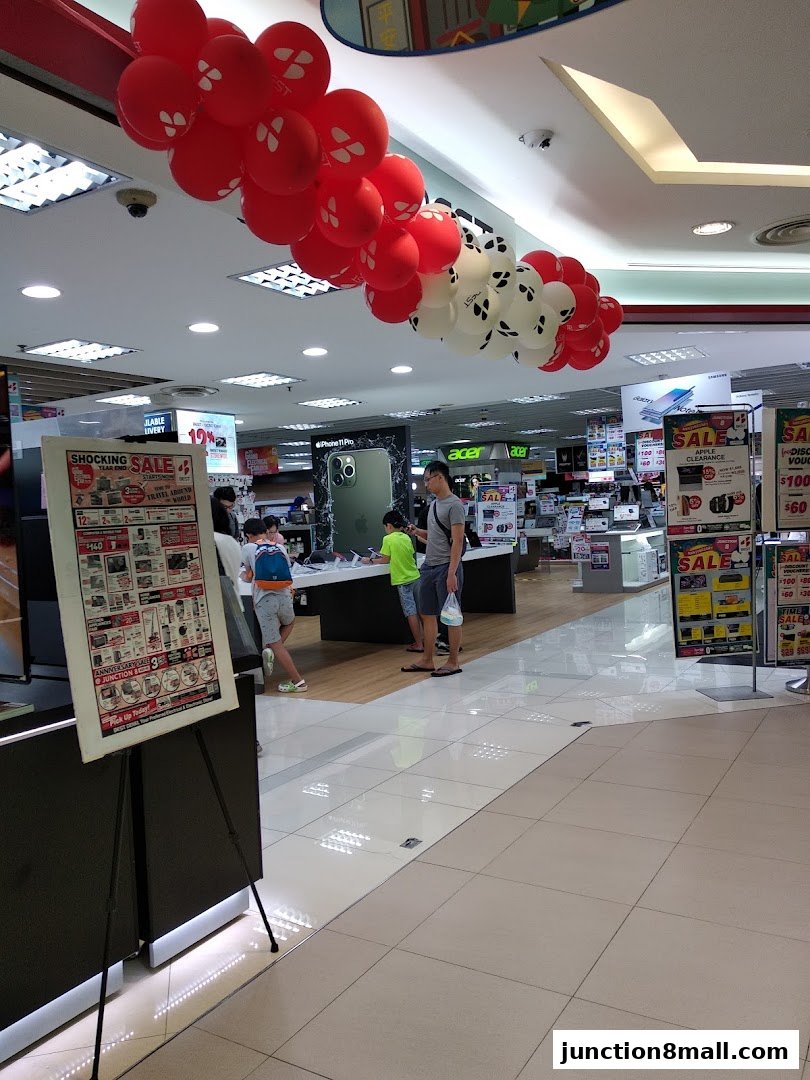 Interior of an electronics store with sale posters and balloons.