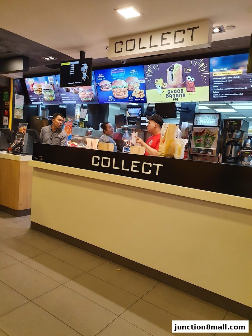 McDonald's counter with staff serving customers and digital menu boards displaying food items.
