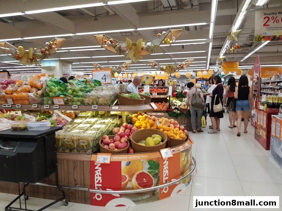 A well-lit supermarket aisle filled with fresh produce and shoppers.