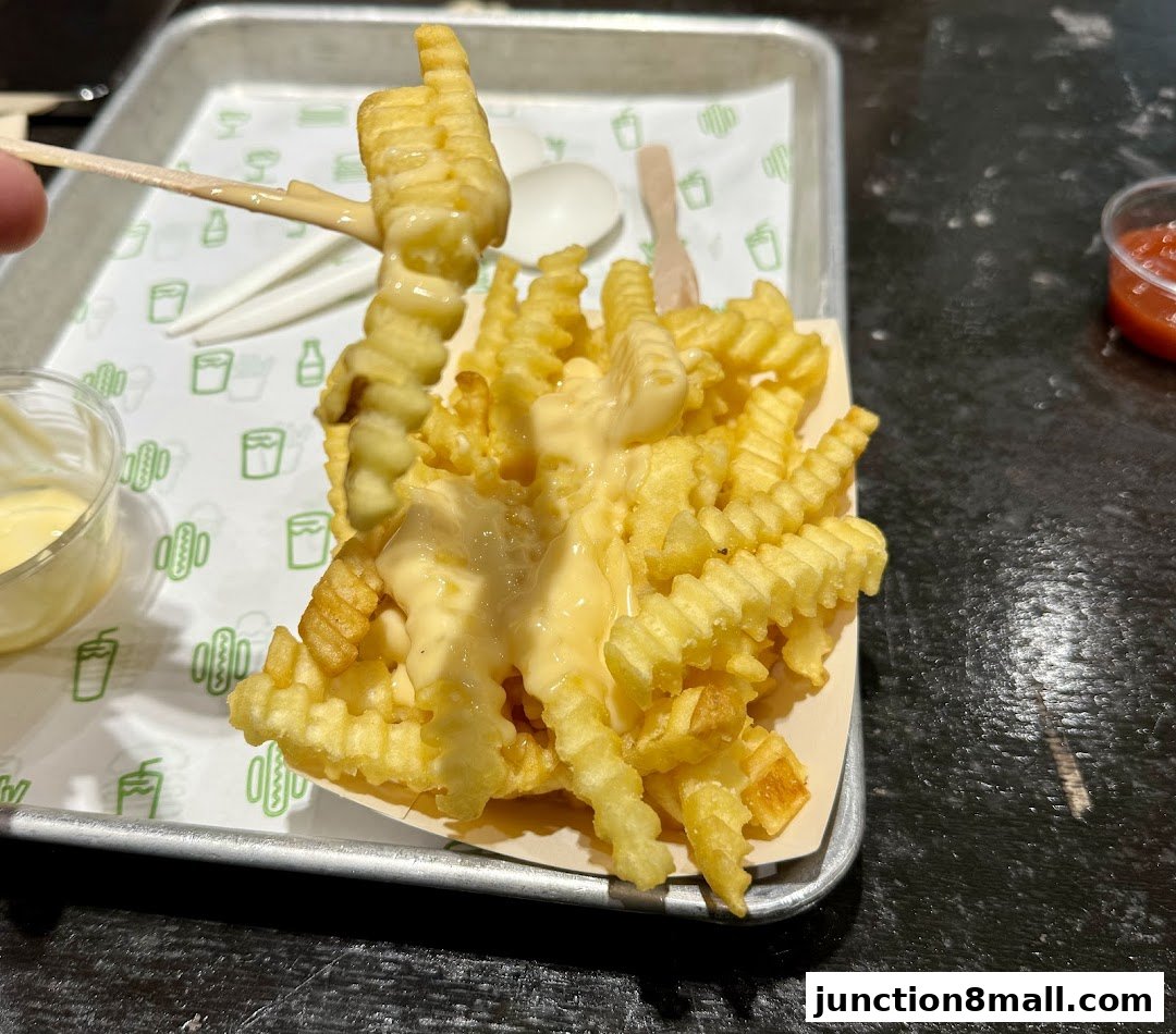 A close-up shot of crinkle-cut fries generously topped with cheese sauce, served with a side of dipping sauce.