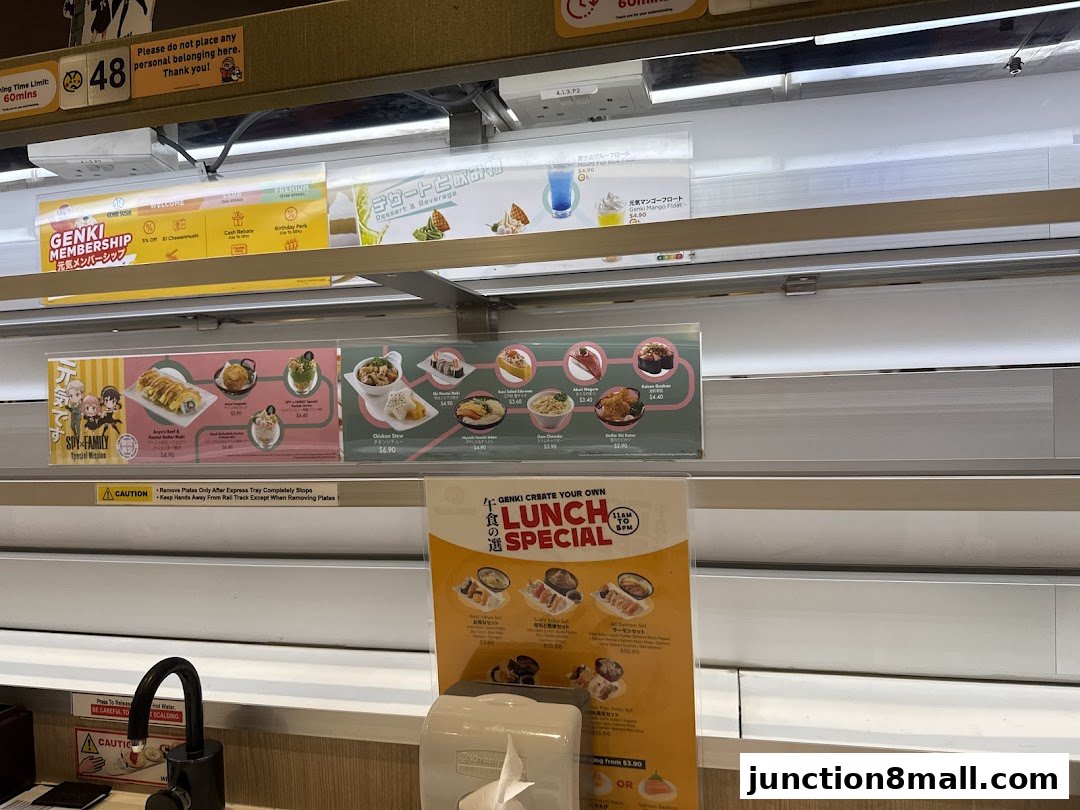 A conveyor belt sushi restaurant with various food items and promotions displayed.