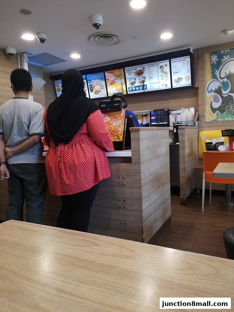 Customers ordering at a Long John Silvers counter with a menu board above.