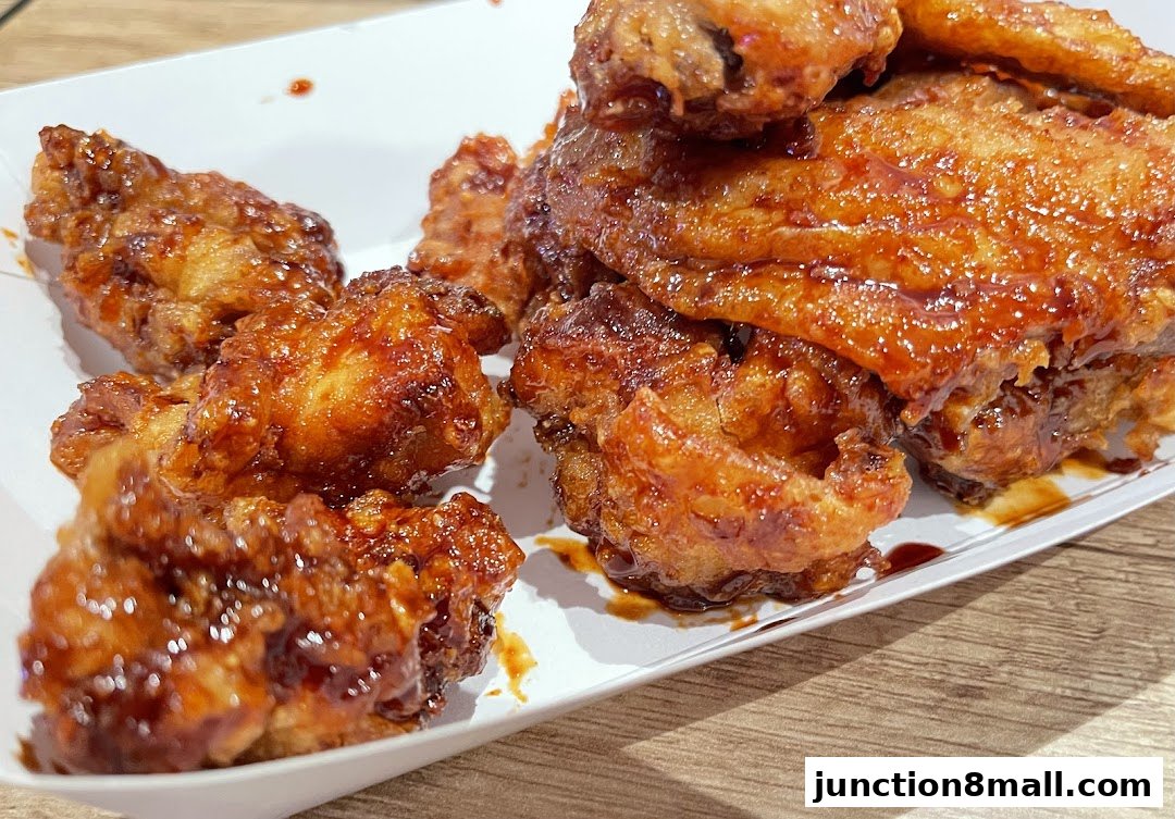 A close-up shot of crispy, glazed chicken wings served in a white container.