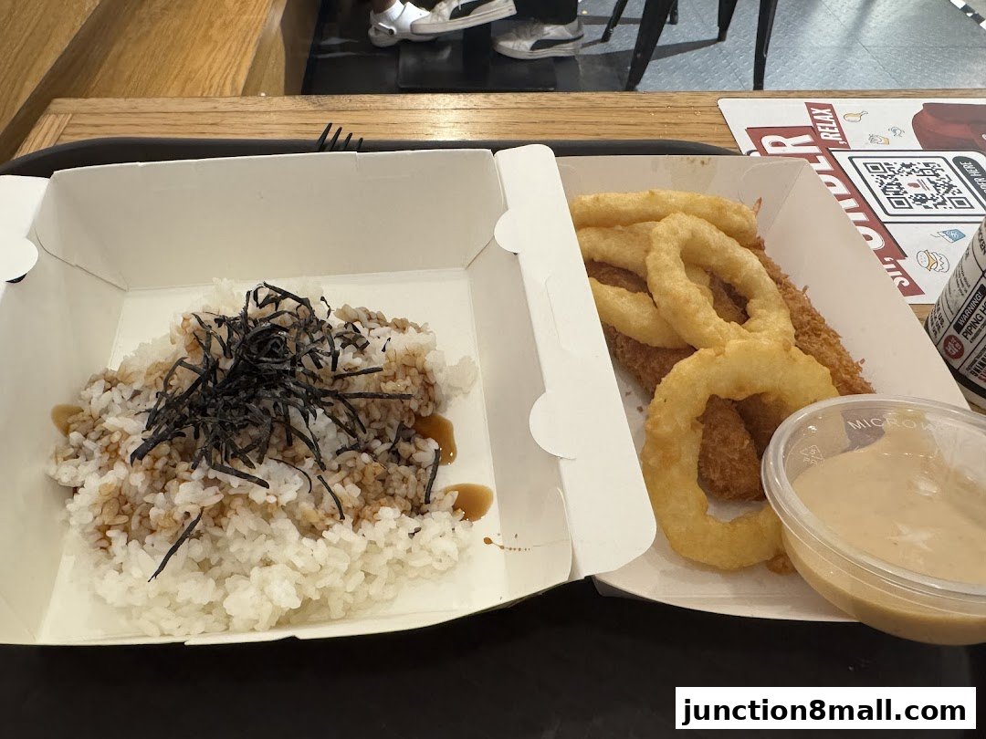 A meal from 4 Fingers Crispy Chicken featuring rice with seaweed and sauce, plus crispy chicken and onion rings with dipping sauce.