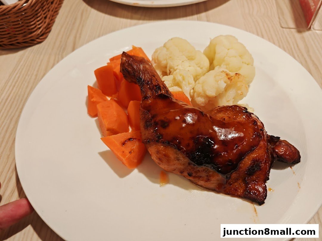 A plate of glazed chicken leg with carrots and cauliflower.