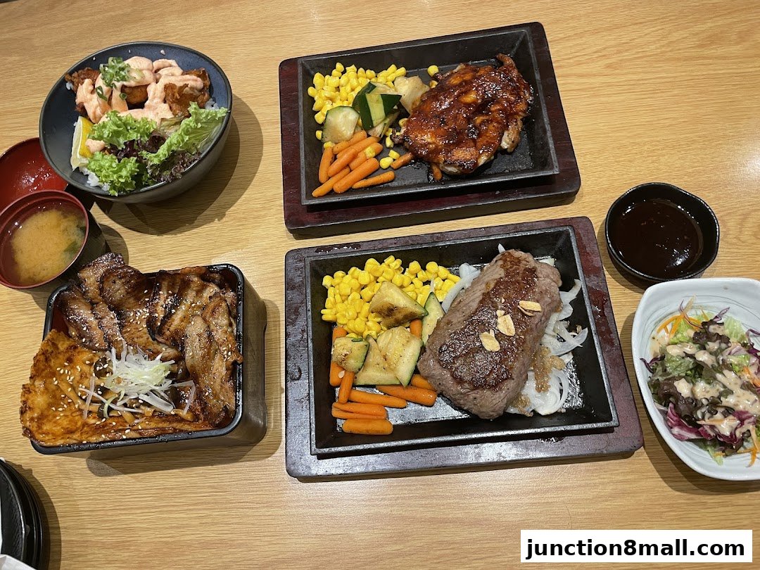 A table laden with various Japanese dishes, including steak, chicken, rice bowls, and salad.