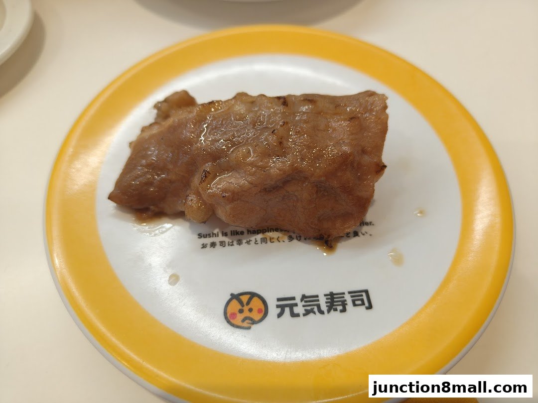 A piece of grilled meat on a plate with the Genki Sushi logo.