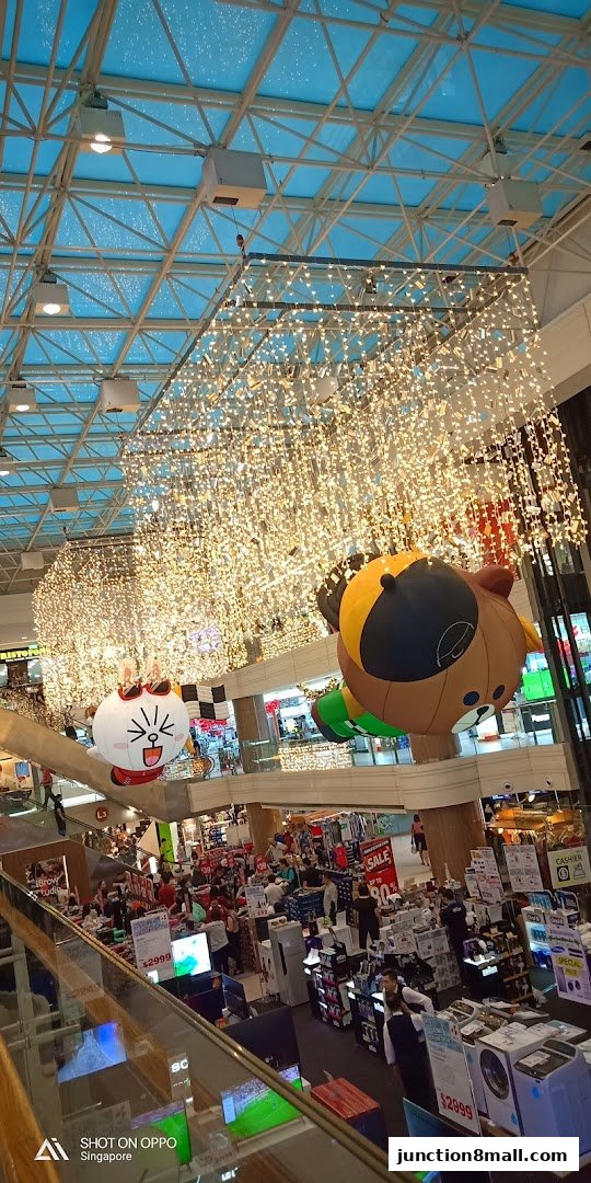 Interior view of a brightly lit mall with festive decorations and shoppers.