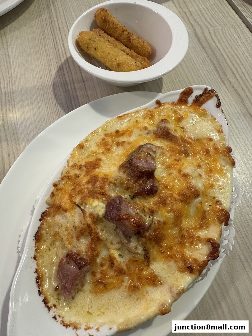 A close-up of a cheesy baked dish with meat and a side of fried mozzarella sticks.