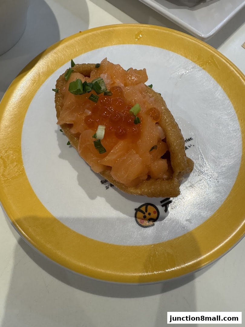 A close-up of a salmon sushi dish with ikura and chives on a yellow-rimmed plate.