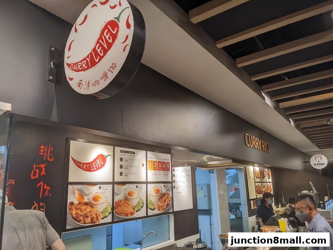 A food stall counter with a menu displaying curry rice dishes and a sign for 'Curry Level'.
