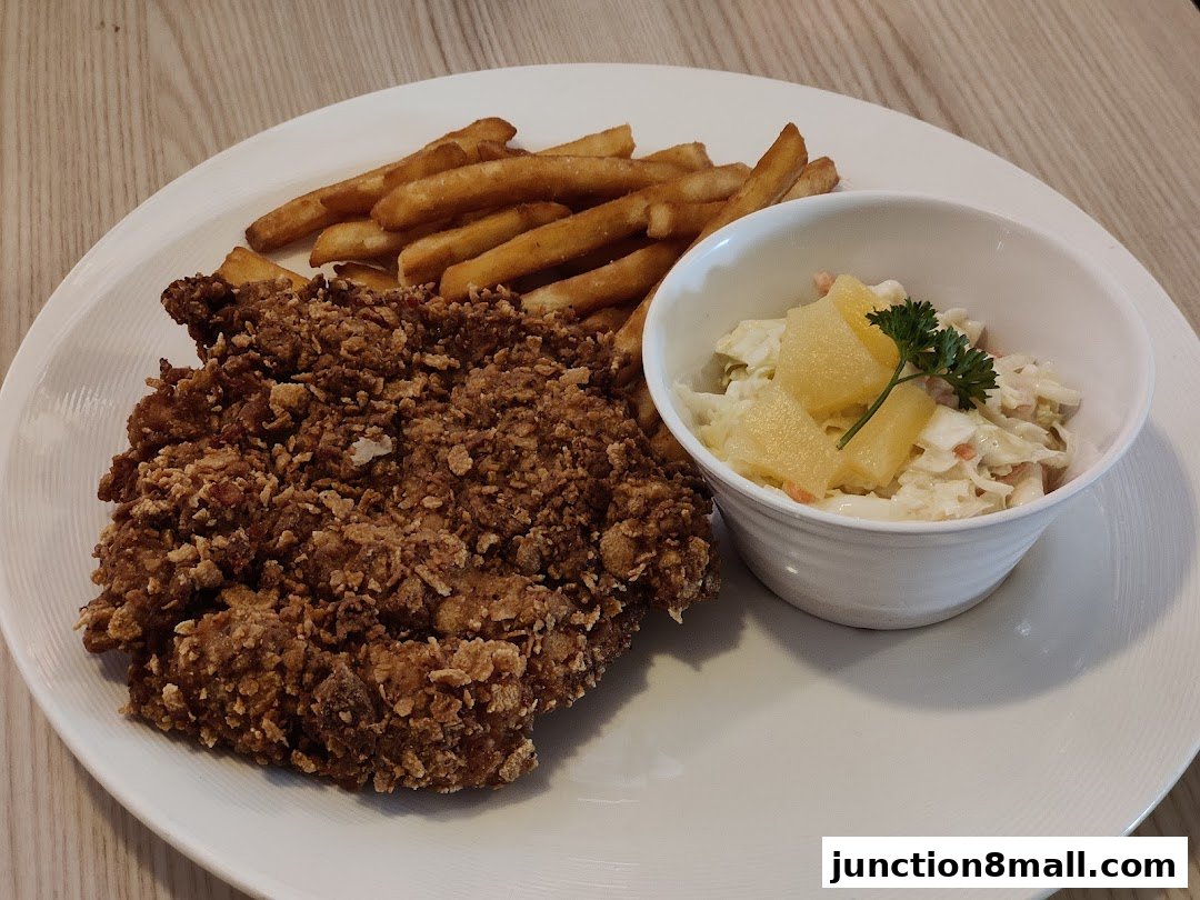 A crispy fried chicken dish with french fries and coleslaw served on a white plate.