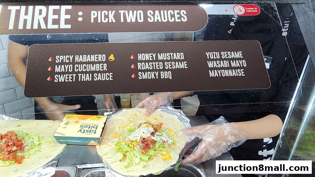 A close-up of a food preparation station showing sauces and ingredients for wraps.