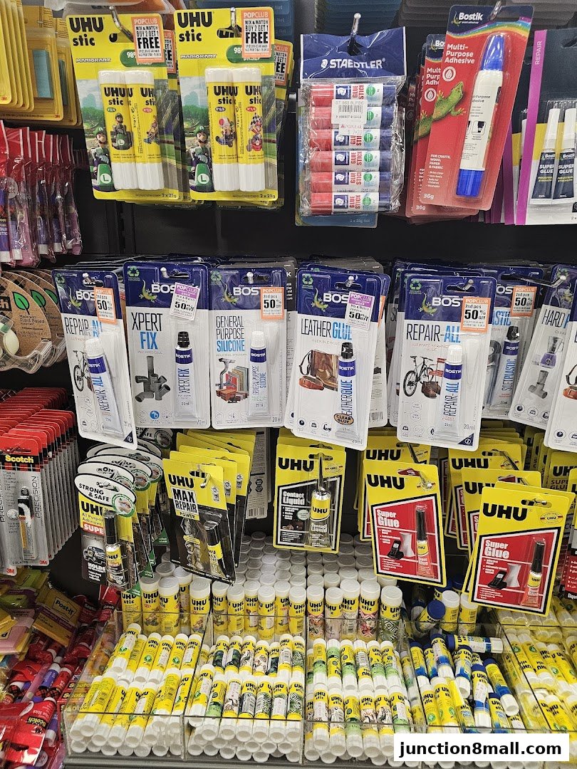 A display of various glues and adhesives, including UHU sticks, Bostik, and Staedtler products.