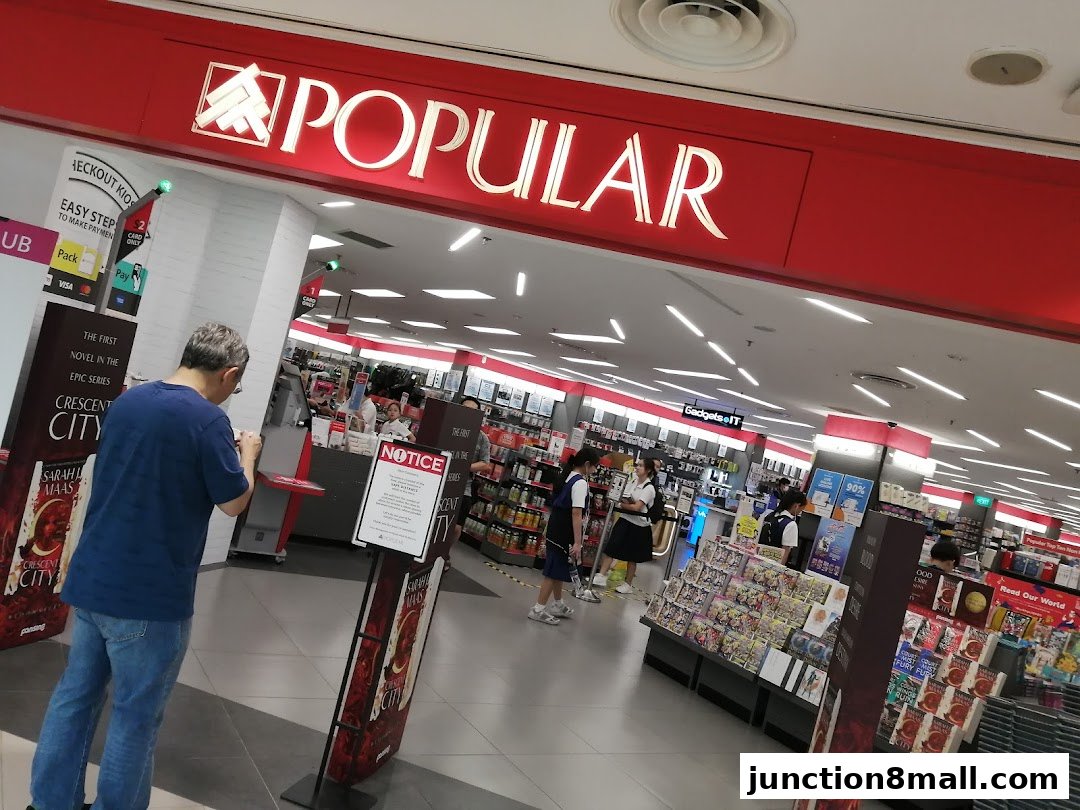 The entrance of a POPULAR bookstore with a customer using a checkout kiosk.