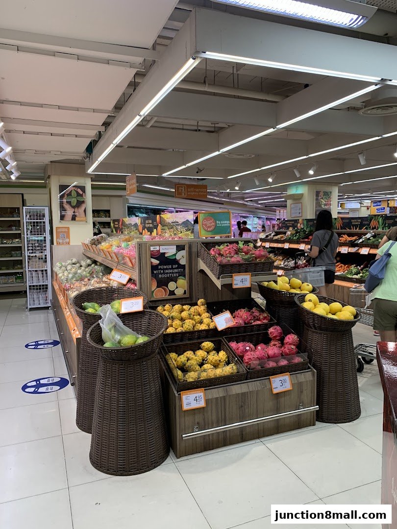 A well-lit grocery store aisle showcasing a variety of fresh fruits like dragon fruit and lemons.
