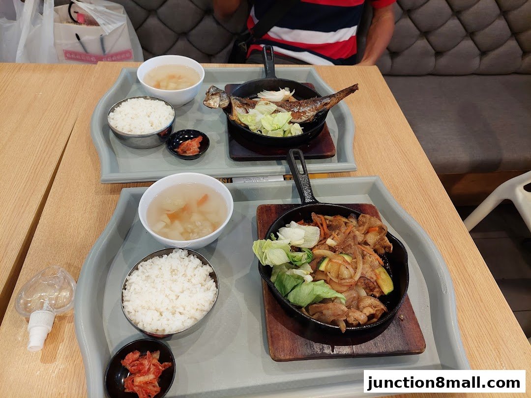 Two trays of Japanese-style meals with rice, soup, and main dishes are served.