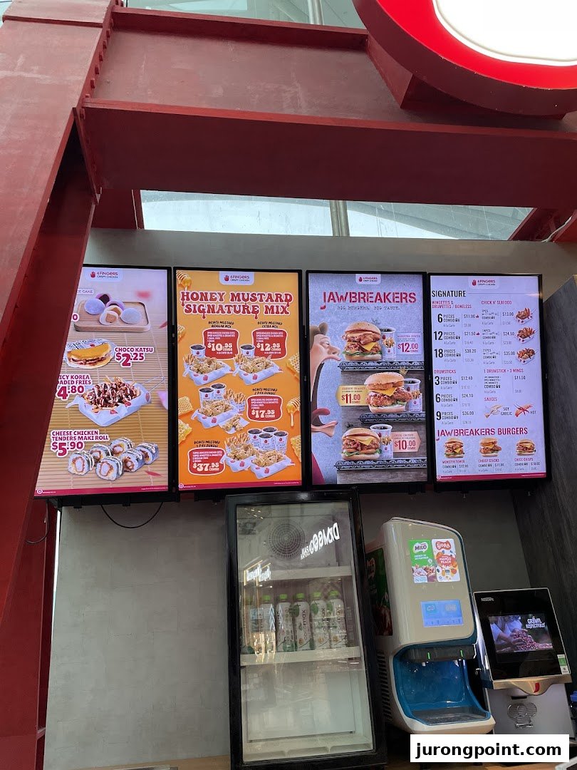 Multiple digital menu boards display food items, prices, and promotions at 4Fingers Crispy Chicken.