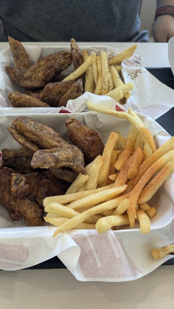 Two baskets of crispy chicken wings and seasoned french fries from 4Fingers Crispy Chicken.