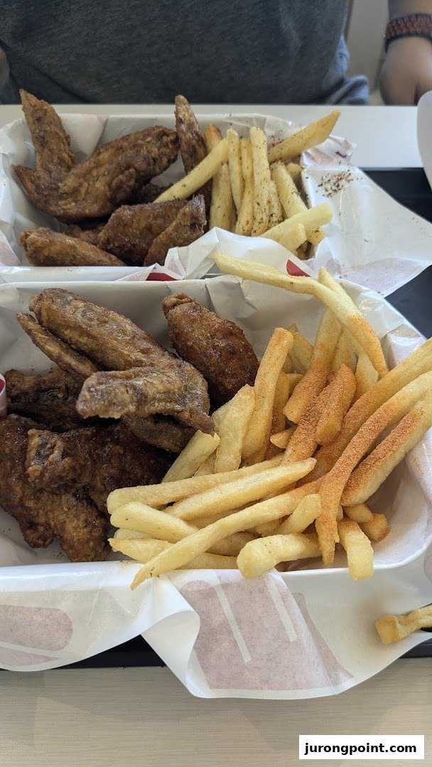 Two baskets of crispy chicken wings and seasoned french fries from 4Fingers Crispy Chicken.