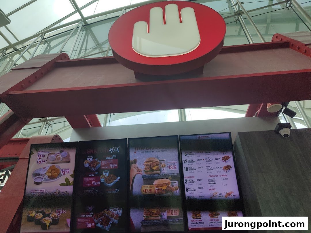 Digital menu boards displaying various chicken meals, burgers, and sides at 4Fingers Crispy Chicken.
