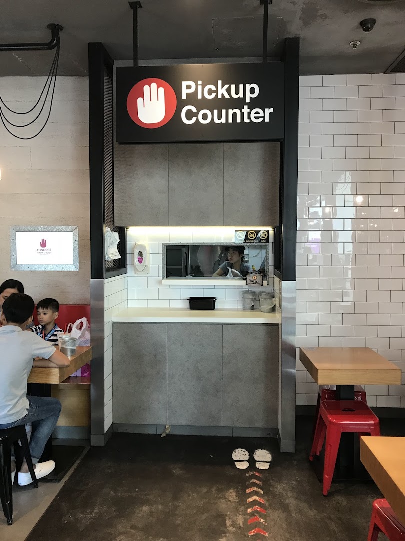 The 4Fingers Crispy Chicken pickup counter with a customer waiting area and modern interior design.