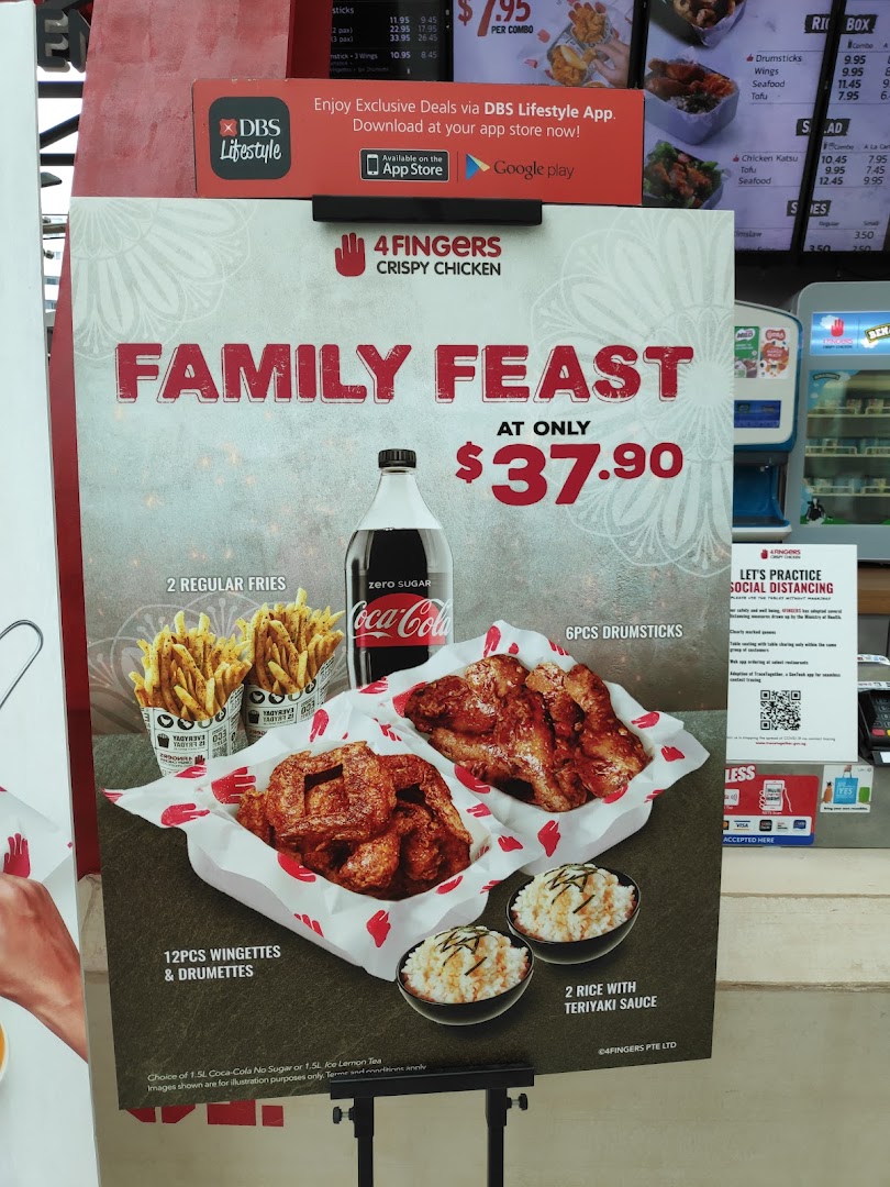 A promotional standee for 4Fingers Crispy Chicken's 'Family Feast' combo, featuring chicken, fries, rice, and a drink.