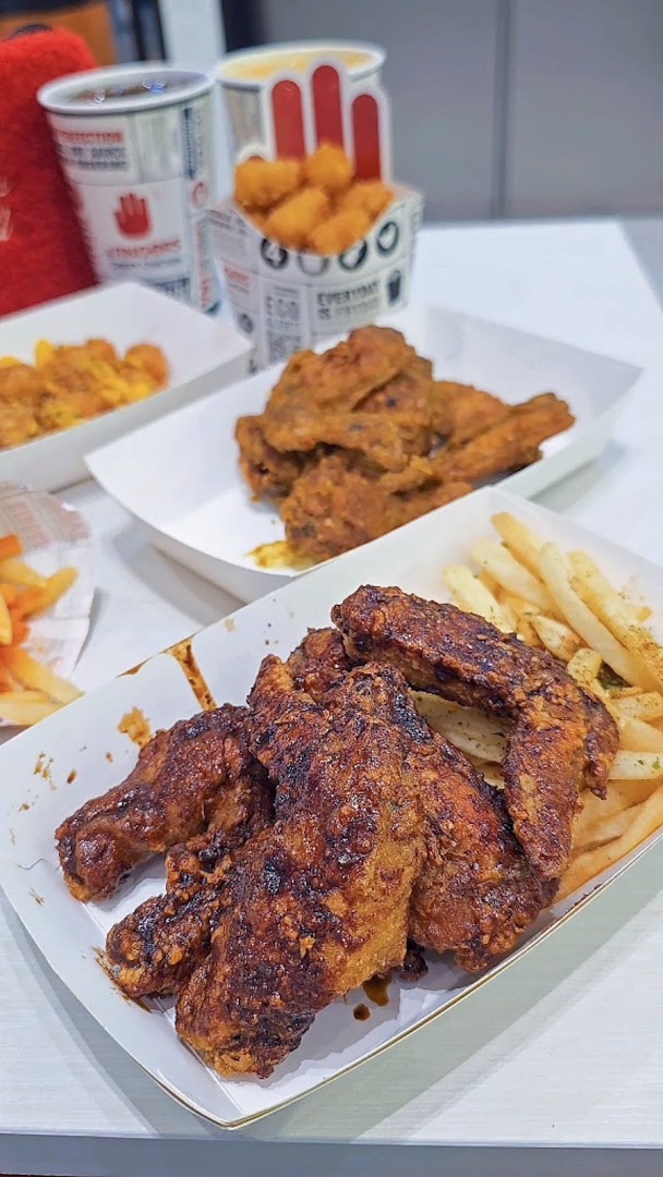 A table laden with crispy fried chicken wings, golden fries, and tater tots from 4Fingers Crispy Chicken.