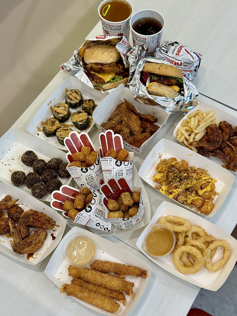 A table laden with a variety of crispy chicken, burgers, sides, and drinks from 4Fingers Crispy Chicken.
