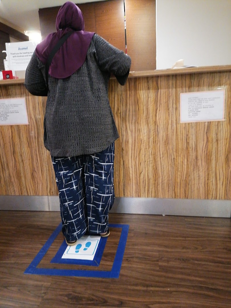 A person stands at AcuMed Medical's reception desk, with social distancing markers visible.