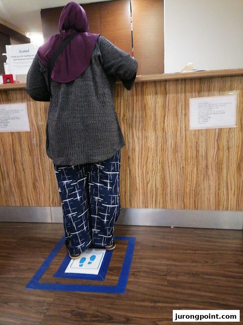A person stands at AcuMed Medical's reception desk, with social distancing markers visible.